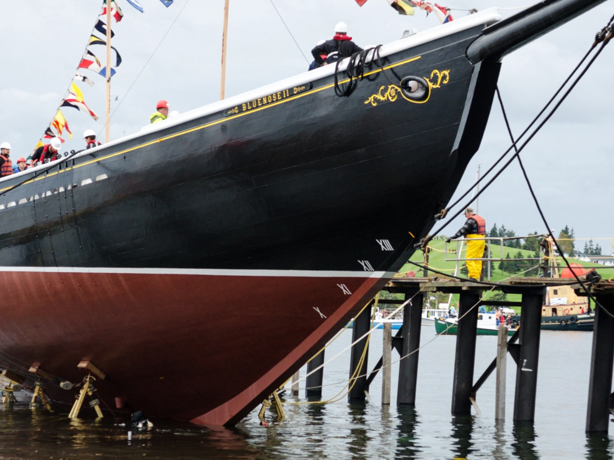Workers in life vests on dock alongside bow of Bluenose II