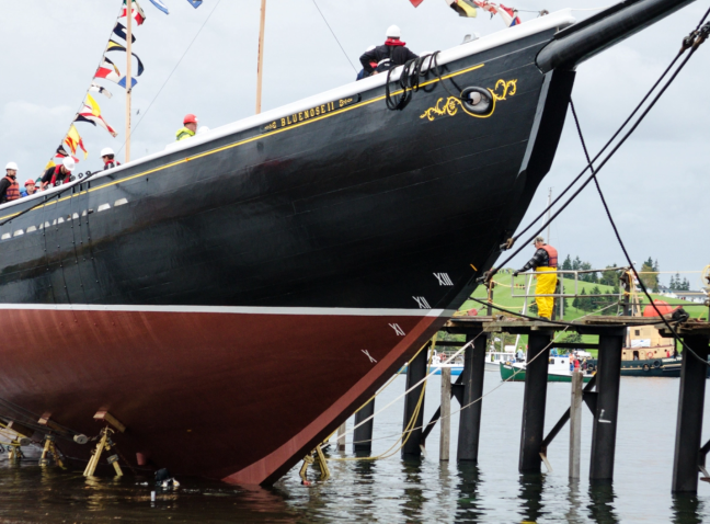 Workers in life vests on dock alongside bow of Bluenose II