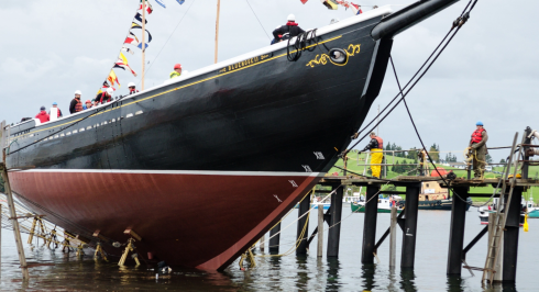 Workers in life vests on dock alongside bow of Bluenose II