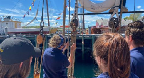 Crew members in navy blue shirts working with ropes on a ship.