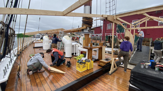 People working on the wooden deck of a ship.
